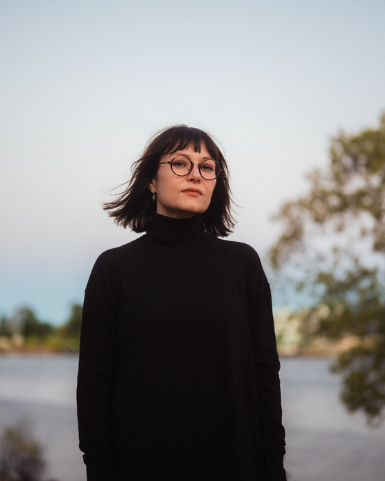 Leah Kardos in a black turtleneck by the Brisbane river at dusk, 2024